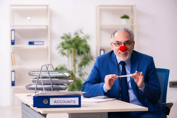 Old businessman clown working in the office