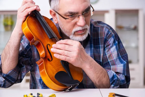 Senior male repairman repairing musical instruments at home — Stock Photo, Image