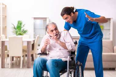 Tekerlekli sandalyedeki yaşlı adam ve genç kötü bakıcı.