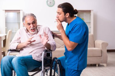 Tekerlekli sandalyedeki yaşlı adam ve genç kötü bakıcı.