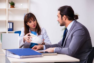 Genç bayan doktor ve hasta iş adamı ofiste.