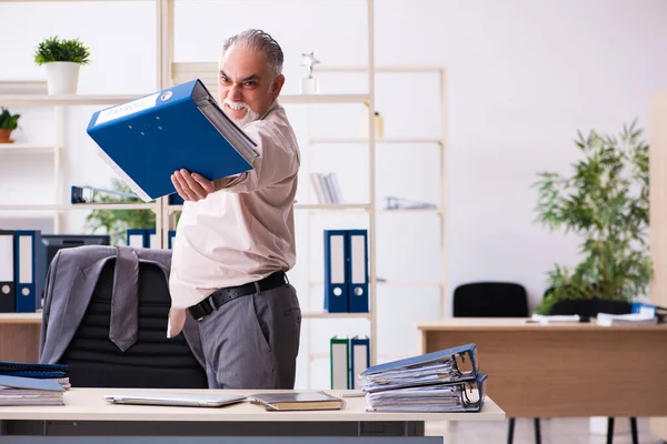 Old male employee doing physical exercises at workplace — Stock Photo, Image