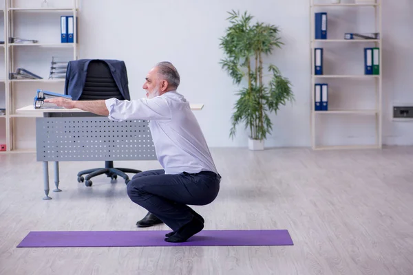 Ältere männliche Mitarbeiter machen in der Pause körperliche Übungen — Stockfoto