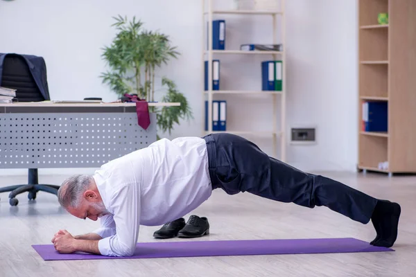 Ältere männliche Mitarbeiter machen in der Pause körperliche Übungen — Stockfoto