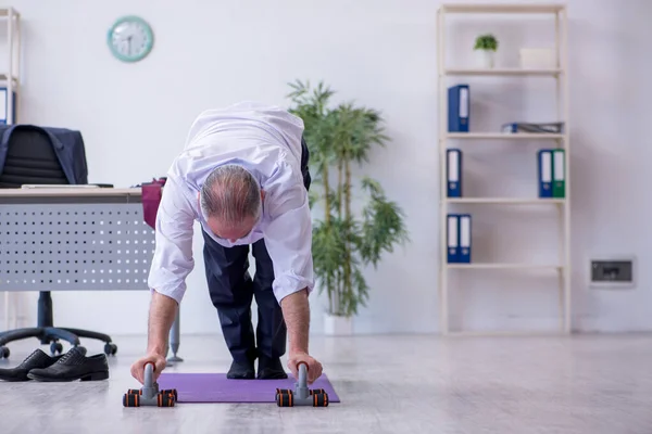 У віці чоловік працівник робить фізичні вправи під час перерви — стокове фото