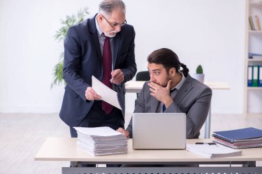 Eski patron ve genç asistanı ofiste çalışıyor.