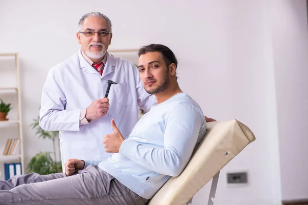 Genç hasta bir adam yaşlı bir doktoru ziyaret ediyor. — Stok fotoğraf