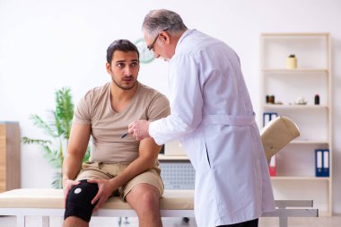 Deneyimli doktor travmatolog genç erkek hastayı muayene ediyor.
