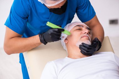 Yaşlı adam estetik ameliyat için erkek doktoru ziyaret ediyor.