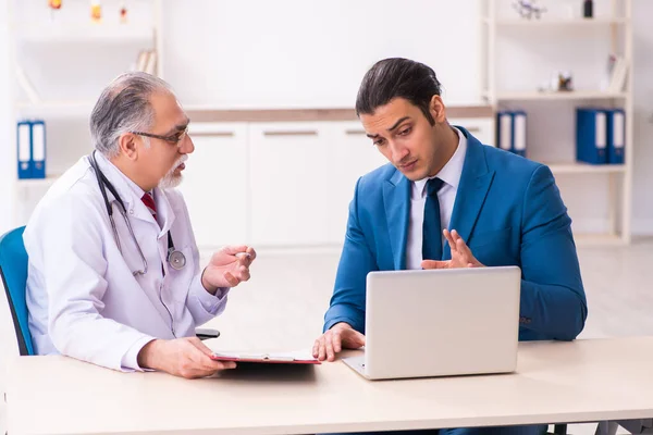 Jeune homme d'affaires rencontre avec un vieux médecin — Photo