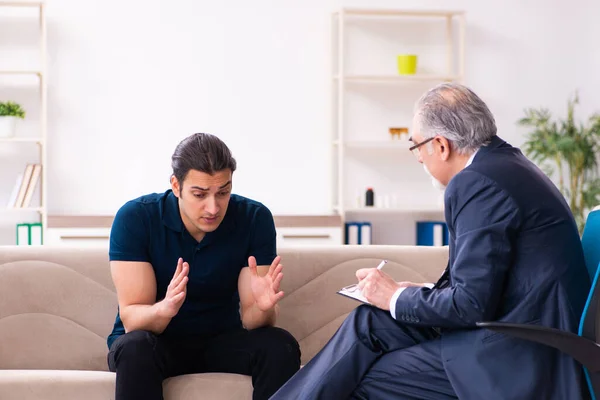 Young man visiting old male psychologist — Stock Photo, Image