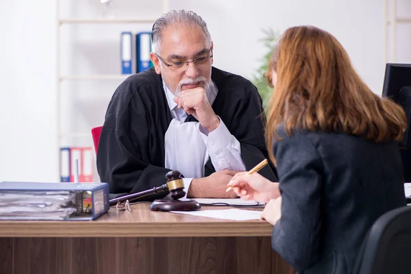 Oude mannelijke rechter en vrouwelijke cliënt in het kantoor — Stockfoto