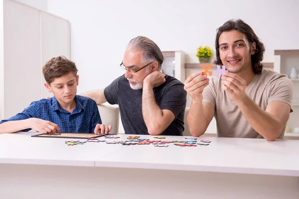 Tres generaciones de familia jugando rompecabezas juego — Foto de Stock