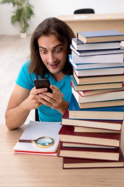 Genç bir erkek öğrenci ve sınıfta bir sürü kitap var.