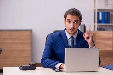 Genç adam işyerinde oturuyor.