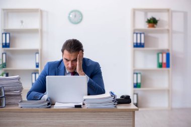 Ofisteki aşırı işten memnun olmayan genç bir erkek işçi.