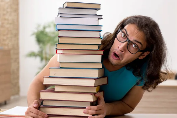 Jovem estudante do sexo masculino e um monte de livros na classe — Fotografia de Stock