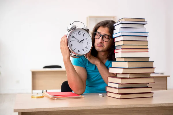 Jovem estudante do sexo masculino e um monte de livros na classe — Fotografia de Stock