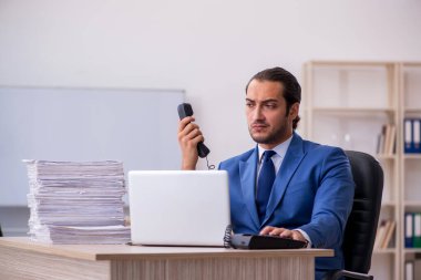 Genç bir erkek çalışan ve ofiste çok fazla iş var.