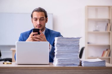 Genç bir erkek çalışan ve ofiste çok fazla iş var.