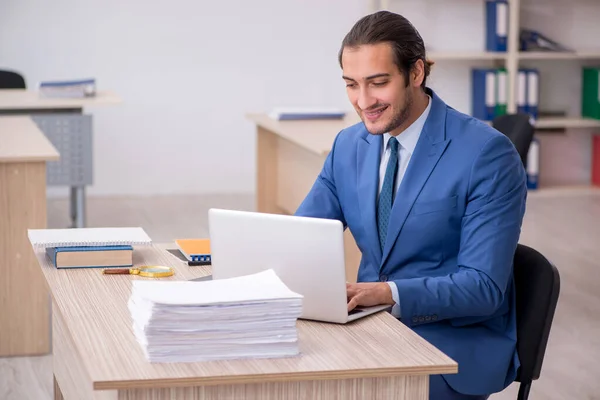 Young male employee and too much work in the office — Stock Photo, Image