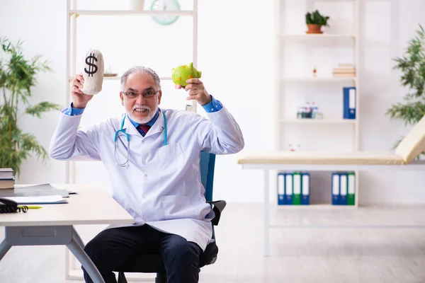 Yaşlı doktor hastanede para çantasını tutuyor. — Stok fotoğraf