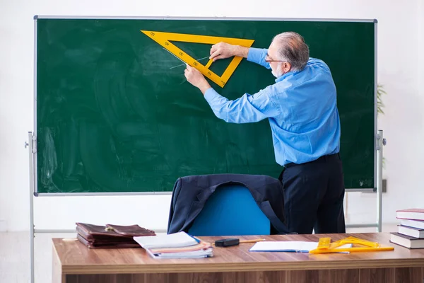 Παλαιό αρσενικό δάσκαλος γεωμετρίας κρατώντας τρίγωνο — Φωτογραφία Αρχείου
