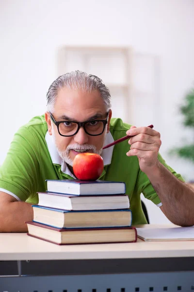 Old male student eating apple during exam preparation — Stock Photo, Image