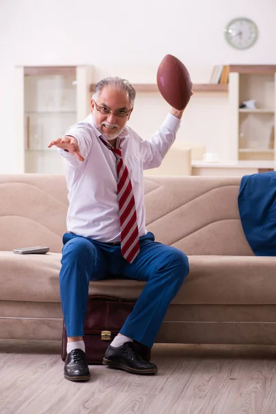 Viejo jefe empleado lanzando pelota de rugby en casa — Foto de Stock