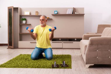 Yaşlı adam evde spor egzersizleri yapıyor.