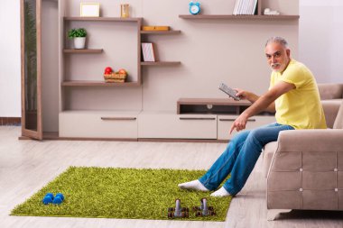 Yaşlı adam evde spor egzersizleri yapıyor.