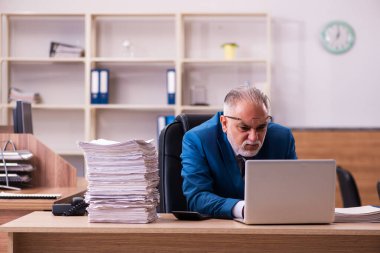 Ofisteki aşırı işten memnun olmayan yaşlı bir erkek işçi.