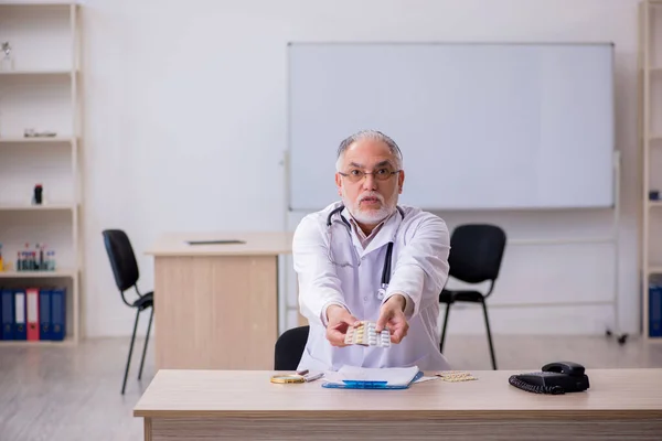 Yaşlı erkek doktor klinikte hap öneriyor. — Stok fotoğraf