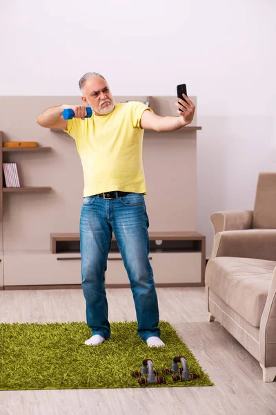 Hombre anciano haciendo ejercicios deportivos en casa —  Fotos de Stock