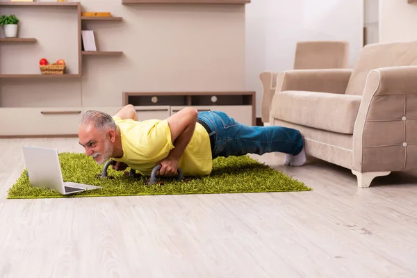 Пожилой человек делает спортивные упражнения дома — стоковое фото