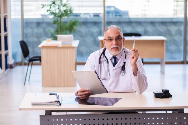 Yaşlı erkek doktor klinikte not alıyor. — Stok fotoğraf