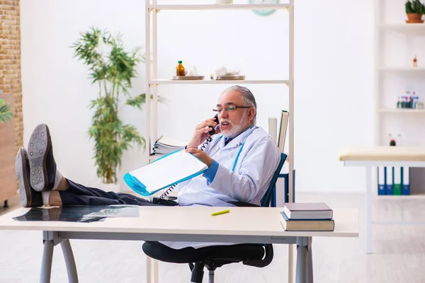 Viejo doctor hablando por teléfono en la clínica —  Fotos de Stock