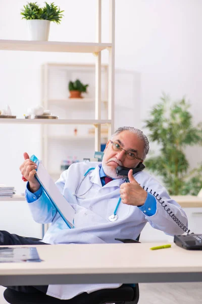 Viejo doctor hablando por teléfono en la clínica — Foto de Stock