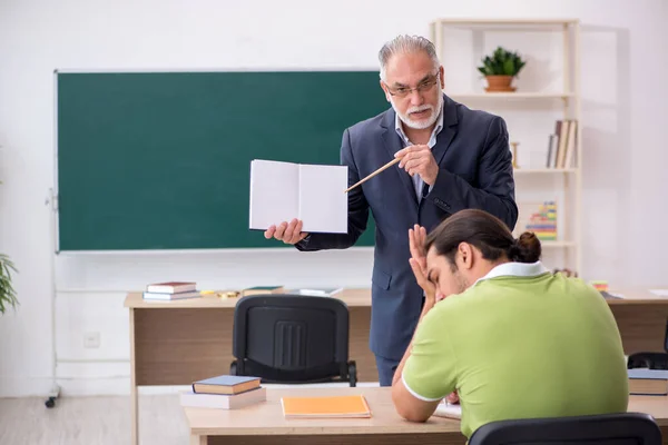 Aged teacher and male lazy student in the classroom