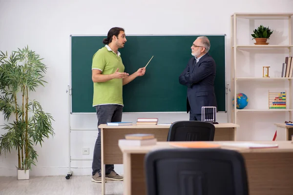 Aged teacher and young male student in the classroom — Stock Photo, Image