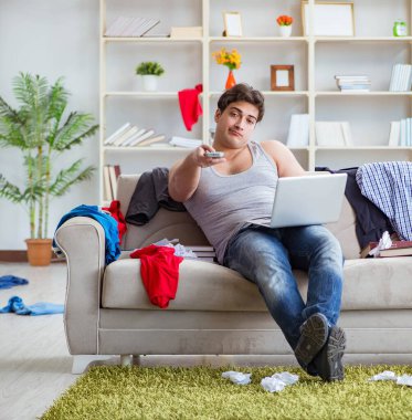 Genç adam dağınık bir odada çalışıyor.