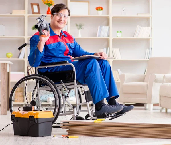 Zdravotně postižený muž pokládající podlahové laminát v úřadu — Stock fotografie