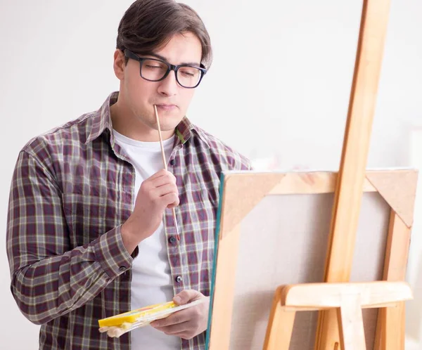 Jovem artista masculino desenho de imagens em estúdio brilhante — Fotografia de Stock