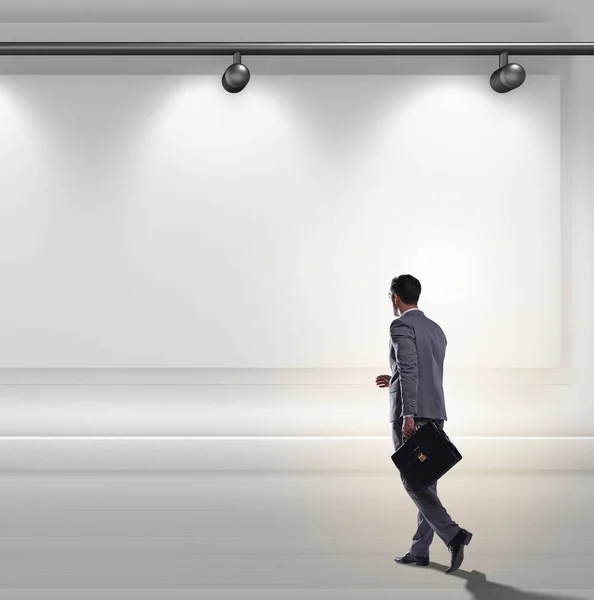 Affärskvinna gående mot väggen lit med spotlights — Stockfoto