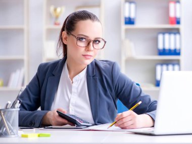 Hesap makinesiyle ofiste çalışan bir muhasebeci.