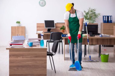 Genç müteahhit ofisi temizliyor.