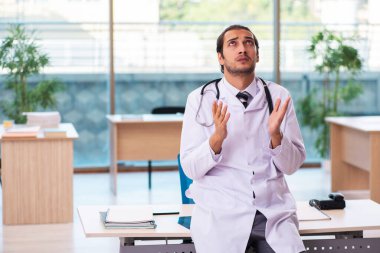 Klinikte çalışan genç erkek doktor.