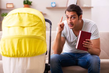 Genç erkek müteahhit evde yeni doğan çocuğa bakıyor.