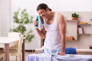 Genç erkek çalışan sabah ütü yapıyor.