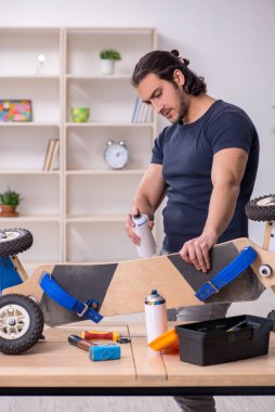 Kaykay tamir eden genç bir erkek tamirci.